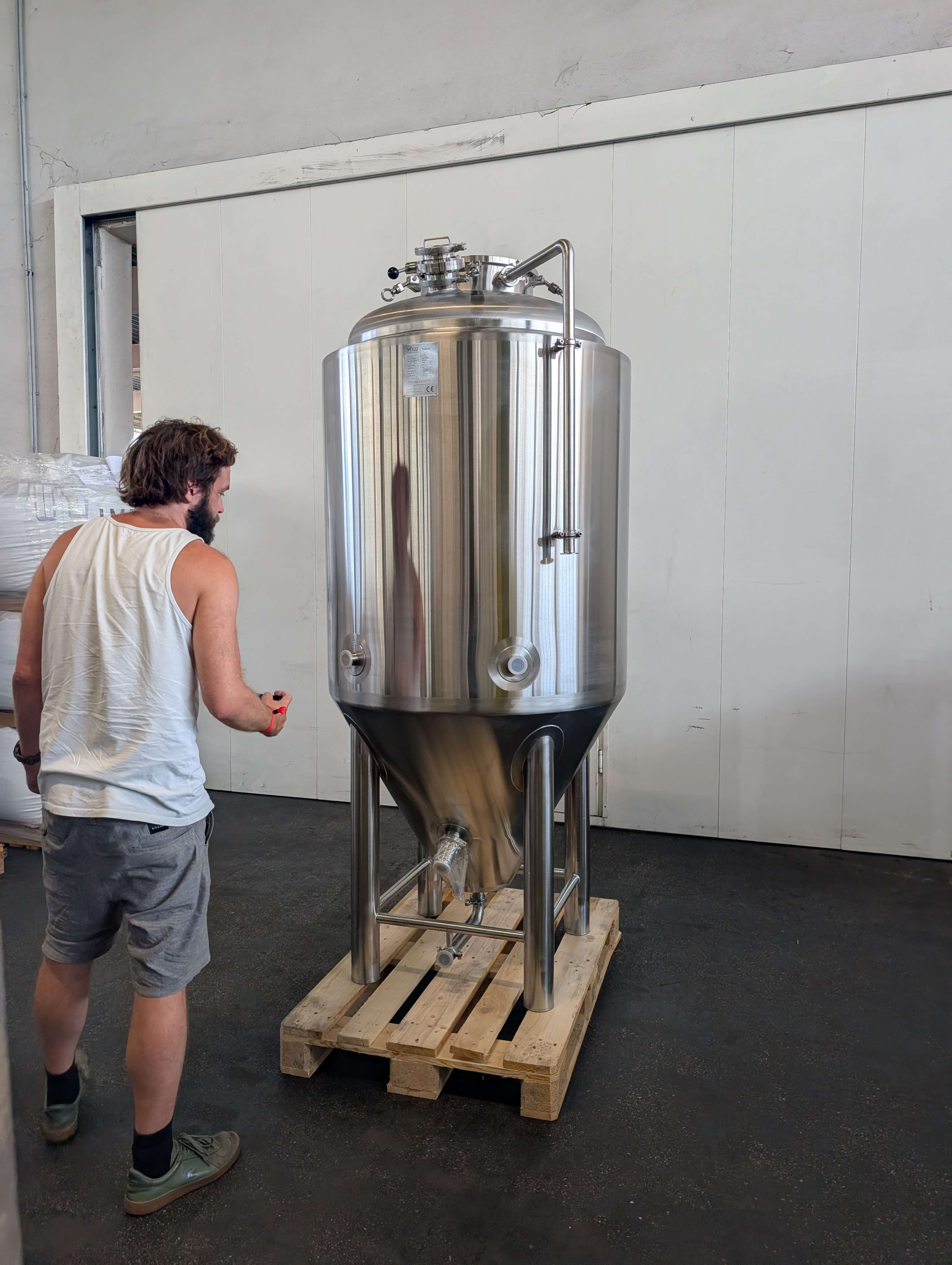 Größenverhältnis eines 500L Craft Beer Gärtanks aus Edelstahl neben einem Brauer in der Halle.